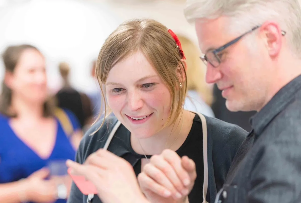 two people watching a video on a phone at a conference