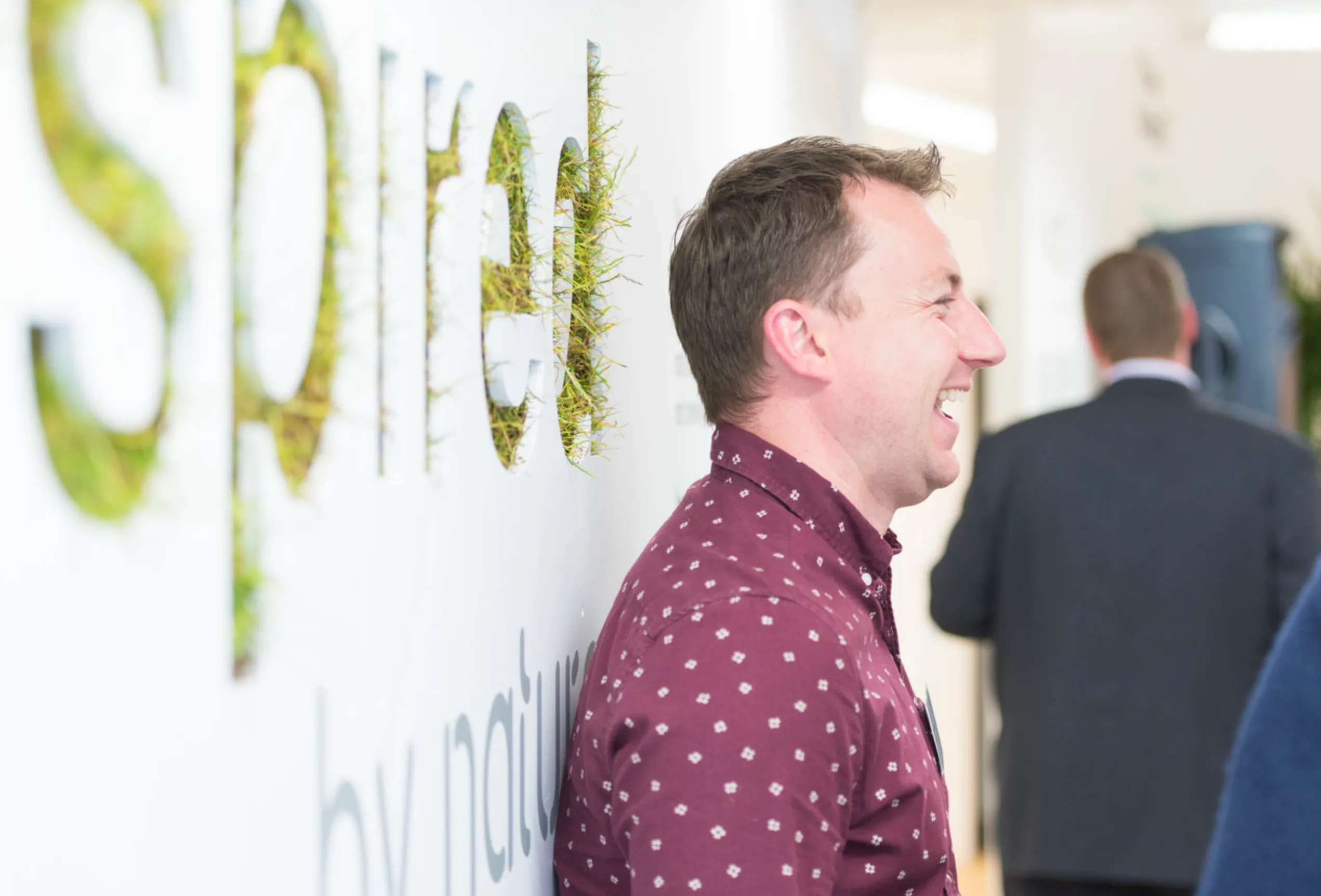 A man laughing stood in front on a grass wall